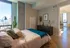 Modern bedroom with large window view, cozy decor, and access to a bright living area.
