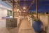 Chic outdoor kitchen with modern design, featuring sleek countertops, stainless steel grills, and ambient string lighting, perfect for evening entertainment against a cityscape backdrop.