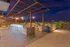 Luxurious rooftop terrace with sleek outdoor kitchen and modern bar seating, overlooking breathtaking city skyline at dusk.