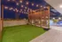 Luxurious rooftop patio showcasing a stylish outdoor gym area with string lights, vibrant seating, and captivating night views.