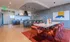 Elegant communal space featuring a modern kitchen with bar seating and a stylish dining area adorned with contemporary art and vibrant red chairs.