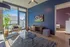 Bright, modern living room with stylish furniture, sleek TV setup, and expansive city views through large windows.