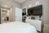 Chic bedroom with modern decor, sleek white dresser, wall-mounted TV, and cozy open access to dining and bathroom areas.
