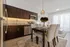 Elegant open-concept dining area with a modern kitchen, featuring dark wood cabinets, stainless steel appliances, and ambient lighting.