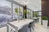 Modern dining area with a sleek white table, contemporary lighting, and stylish greenery in a spacious setting.