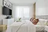 Elegant bedroom with plush bedding, modern decor, and abundant natural light filtered through sheer curtains.