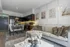 Modern open-concept living space featuring a stylish kitchen, dining area, and cozy sofa with decorative pillows, enhanced by chic wall art.