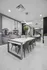 Modern dining area with sleek white table, stylish gray chairs, and elegant lighting, complemented by artistic wall decor and lush greenery.