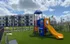 Vibrant apartment complex with a colorful playground, lush green lawn, and modern exterior architecture.