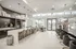 Luxurious contemporary kitchen and lounge area featuring sleek white countertops, elegant pendant lighting, stylish bar stools, and abundant natural light.