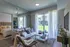 Bright and cozy living room with elegant decor, plush sofa, and floor-to-ceiling windows offering a lush garden view.