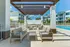 Modern outdoor patio area with stylish seating under a pergola, overlooking a sparkling pool and surrounded by lush landscaping.