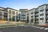 Modern apartment complex showcasing sleek architectural design with large windows and private balconies, surrounded by landscaped gardens and ample parking spaces.