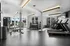 Modern fitness center with natural light, fully equipped with treadmills, free weights, and exercise machines.