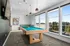 Modern recreational room with a stylish pool table, large windows offering scenic views, and contemporary decor lighting.