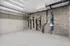 Modern bike storage room with secure racks, concrete walls, and sleek overhead piping in a spacious apartment building.