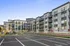 Modern apartment complex with sleek architecture, spacious balconies, and ample parking under a clear blue sky.