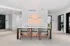 Contemporary dining area with a sleek table and modern chairs, accented by vibrant neon wall art reading 'Living on a Lark'.
