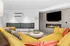 Contemporary living room featuring a vibrant yellow sofa, modern fireplace, and sleek wall-mounted TV, creating a warm and inviting atmosphere.