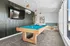 Sleek game room with a stylish pool table, wall-mounted TV, and cozy seating area, perfect for entertaining.