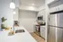 Bright and modern kitchen with sleek stainless steel appliances, elegant white cabinets, and a spacious quartz countertop, perfect for stylish cooking and entertaining.