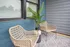 Charming patio featuring cozy woven chairs, lush potted plant, and stylish blue siding for a relaxing outdoor retreat.
