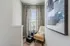 Chic and cozy reading nook featuring a stylish chair, modern abstract artwork, and elegant patterned curtains.