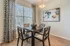 Chic dining area with elegant patterned curtains, stylish artwork, and a modern wooden table set for an inviting ambiance.