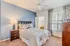 Cozy bedroom with stylish decor, featuring a comfortable bed, modern nightstand, and large window with patterned curtains.