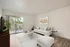 Bright and modern living room with elegant white sofa, chic decor, and a large window leading to a scenic outdoor view.