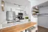 Modern kitchen with sleek stainless steel appliances, white cabinetry, and elegant wooden breakfast bar in a bright, open space.