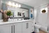 Elegant bathroom featuring a modern double vanity with sleek fixtures, vibrant plant decor, and stylish wall art, offering a refreshing space.