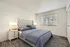 Elegant bedroom with plush headboard, cozy bedding, and natural light from large window.