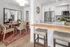 Chic apartment interior showcasing a modern dining area with elegant wicker chairs and a contemporary kitchen equipped with stainless steel appliances and stylish decor.