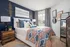 Charming bedroom featuring a bold blue accent wall, elegant decor, and a stylish patterned bedspread, flooded with natural light from a large window.