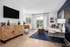 Bright and stylish living room with contemporary decor, featuring a cozy white sofa, chic wooden console, and scenic balcony view.