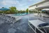 Luxurious outdoor pool area with elegant lounge chairs, vibrant greenery, and inviting blue umbrellas.