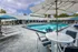 Luxurious outdoor pool area with sleek lounge chairs, shaded tables, and vibrant blue water, offering a perfect oasis for relaxation.