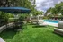 Luxurious outdoor pool area with sun loungers and shaded seating, surrounded by lush greenery and vibrant flowers.
