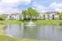 Charming lakeside apartment complex with lush greenery and a tranquil fountain for serene living.