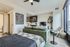 Modern studio apartment featuring a cozy living area with a stylish green couch, sleek kitchen, and expansive windows for natural light.