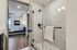 Modern bathroom with elegant glass shower and inviting view of a cozy, stylish bedroom featuring a plush bed and chic decor.