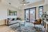 Bright and modern living room with a comfy gray sofa, elegant armchair, stylish rug, and large windows leading to a balcony, creating a welcoming atmosphere.