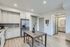 Modern kitchen with sleek stainless steel appliances, elegant cabinetry, and chic dining table, opening into a stylish bathroom.
