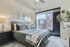 Chic bedroom with modern decor, large window with urban view, and cozy bedding.
