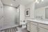 Elegant bathroom featuring a sleek glass shower, modern vanity with ample storage, and stylish wall art.