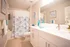 Chic bathroom with elegant white vanity, patterned shower curtain, and stylish blue accents.