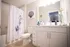 Bright and modern bathroom featuring smooth white cabinetry, elegant floral shower curtain, and stylish seashell wall art, offering a serene ambiance.