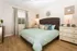 Inviting bedroom with elegant decor featuring a cozy bed, stylish lamps, and natural light from a window with patterned curtains.