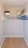 Spacious walk-in closet with elegant wooden flooring and ample shelving for storage solutions.
